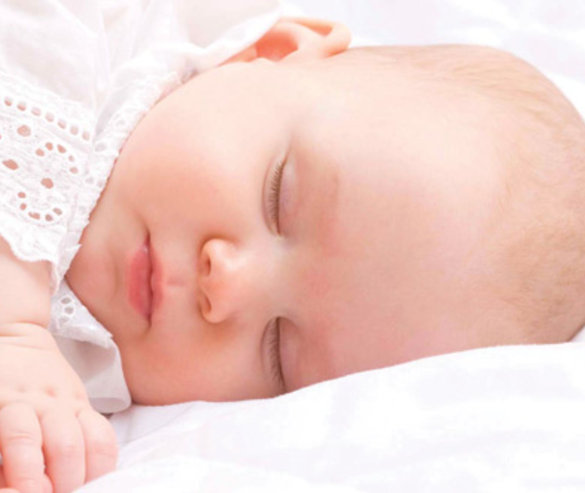 Sleeping baby peacefully resting on a white blanket.