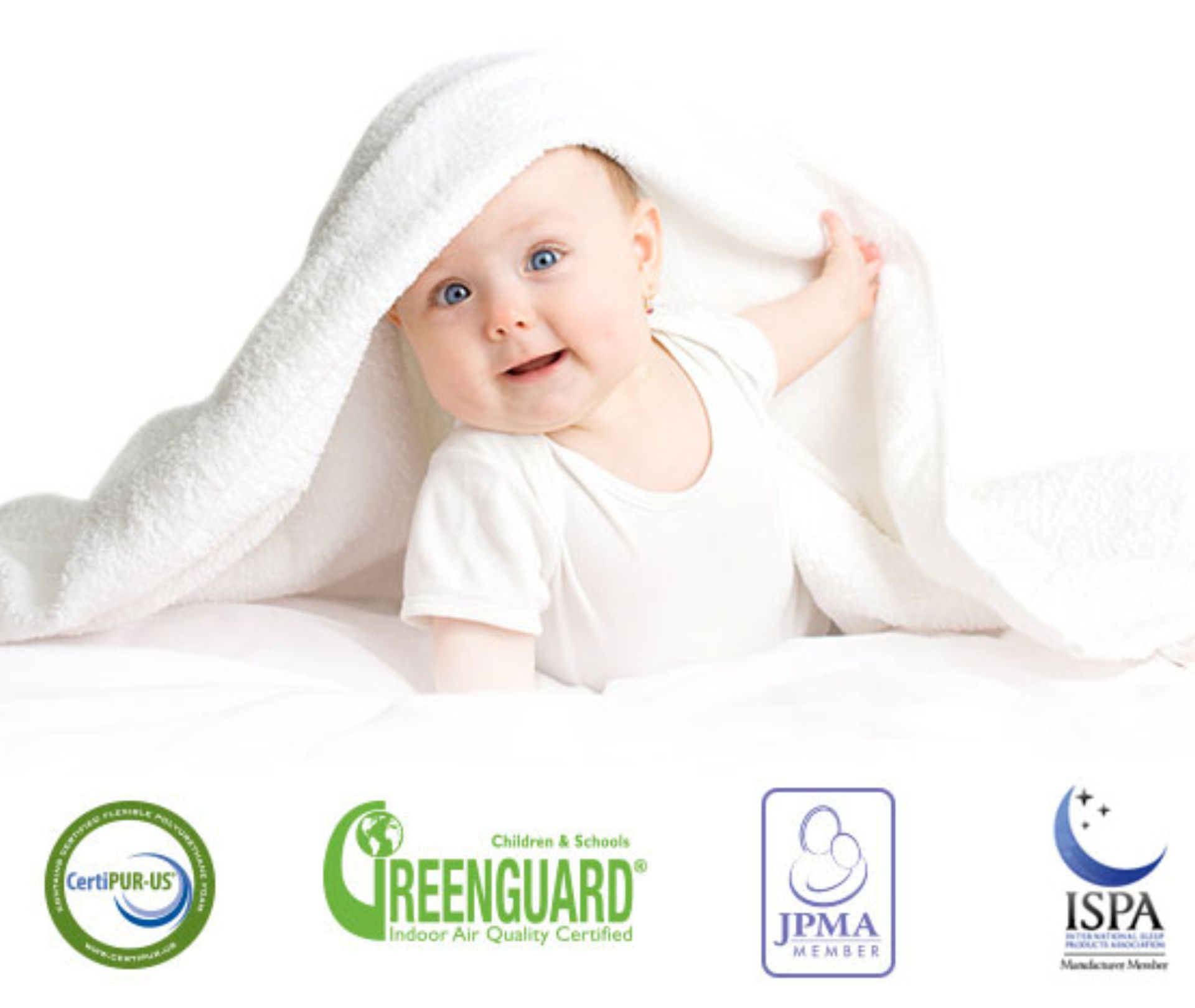 A baby smiling under a white blanket on a white surface.